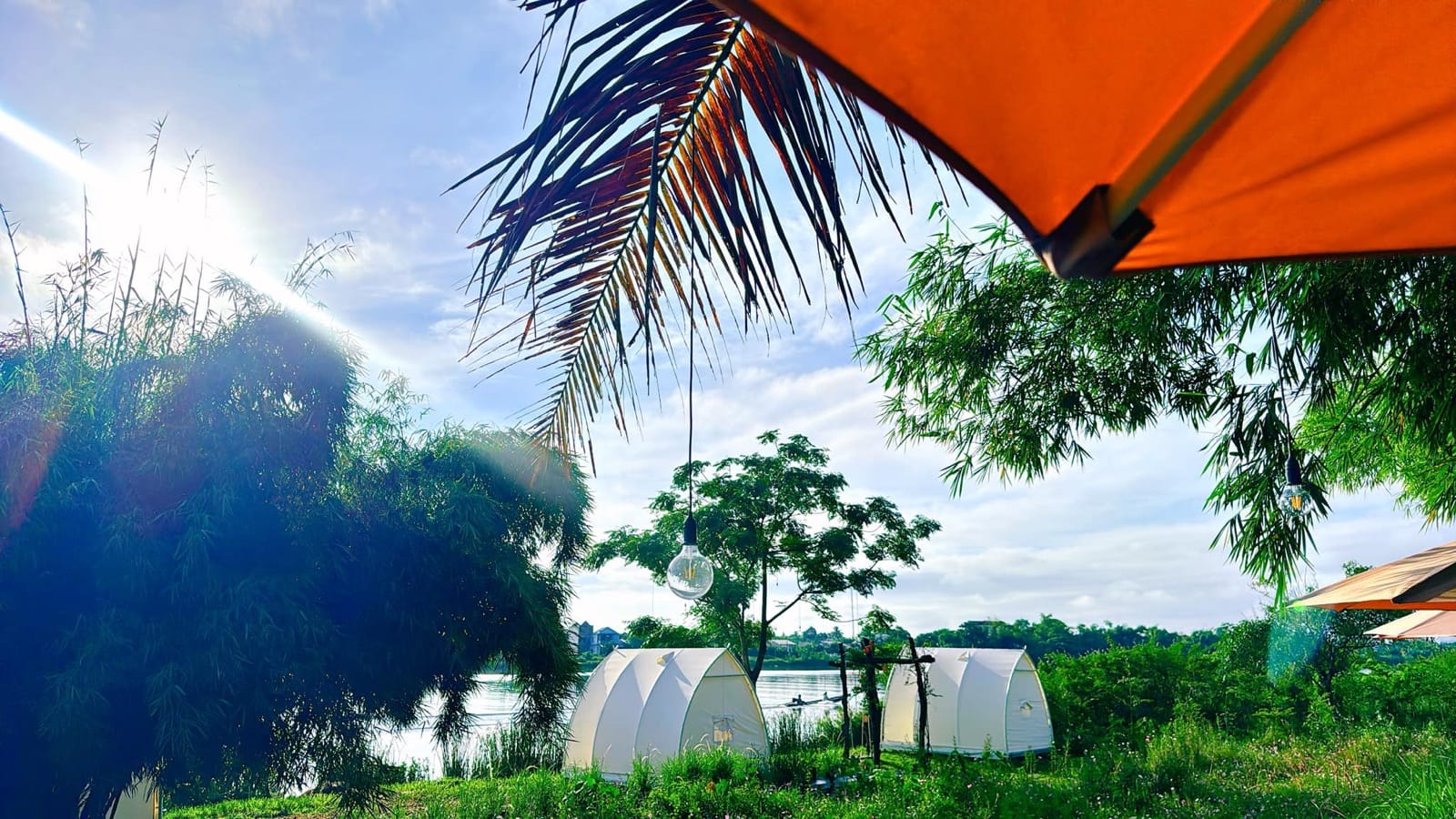 Nắng sớm bên bờ sông Hương — Rặng tre, đèn dây và những chiếc lều glamping